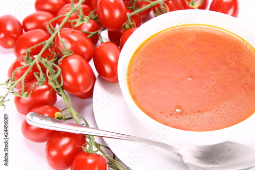 Tomato soup with fresh tomatoes around it and a spoon