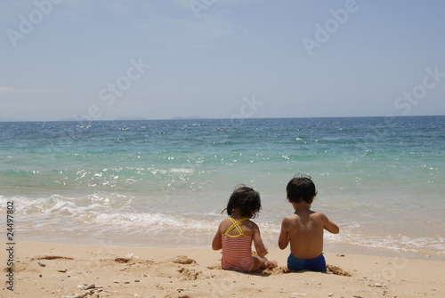 Boy and Girl Sitting Together on Tropical Beach