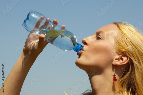 girl drinking water from a plastic bottle