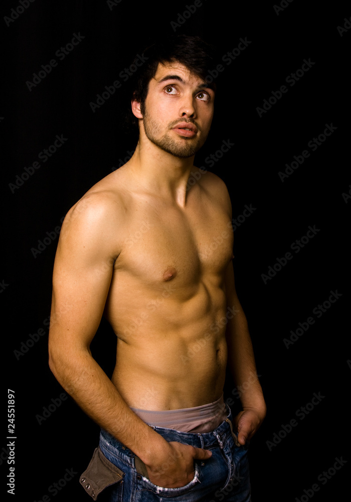 Fototapeta premium Young man with atletic body on black background