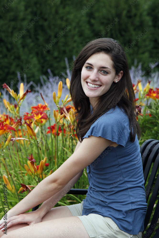 Naklejka premium Young woman sitting on a bench with flowers