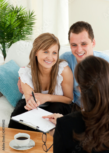 Happy young couple signing a contract sitting in the living room photo