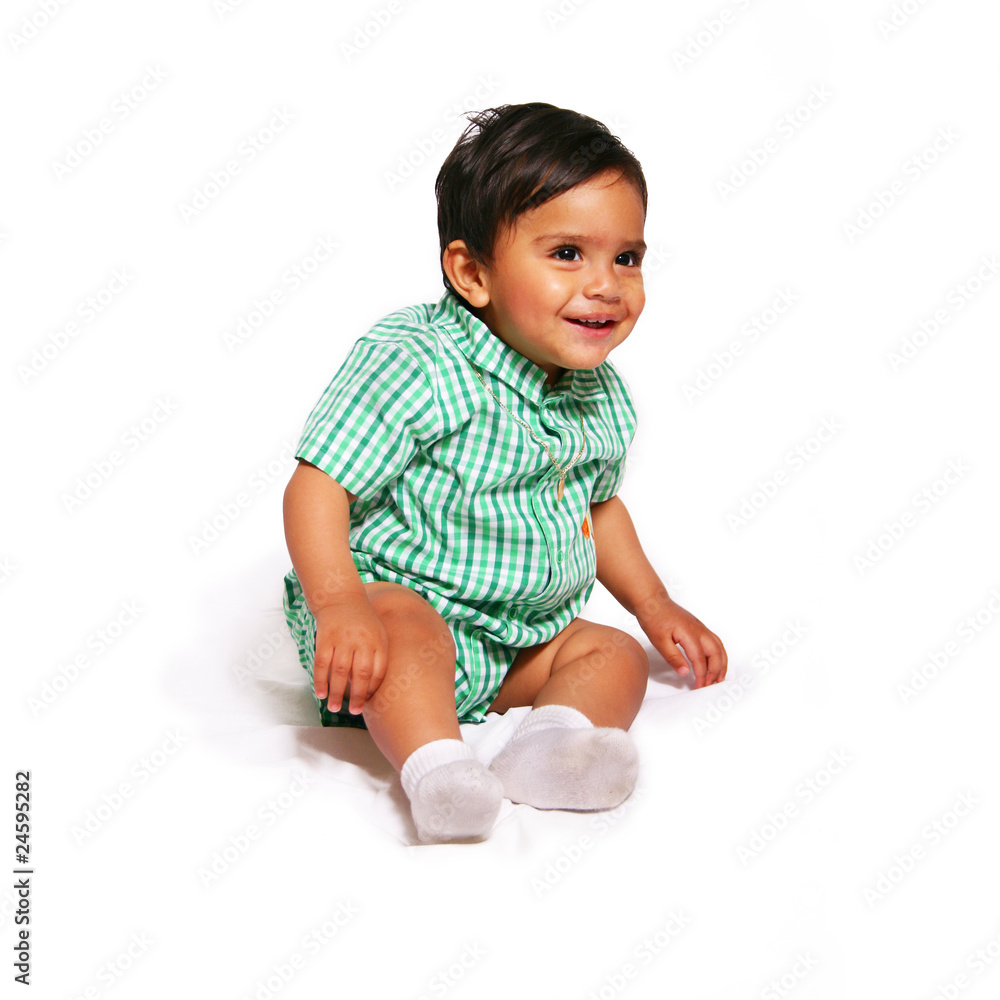 Toddler baby wearing green sitting down smiling Toddler baby wearing green sitting down smiling
