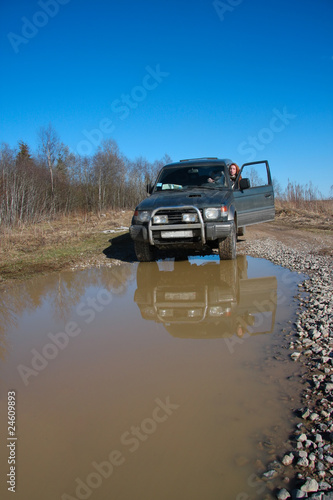 Young woman behind rudder of offroad car on dirt road