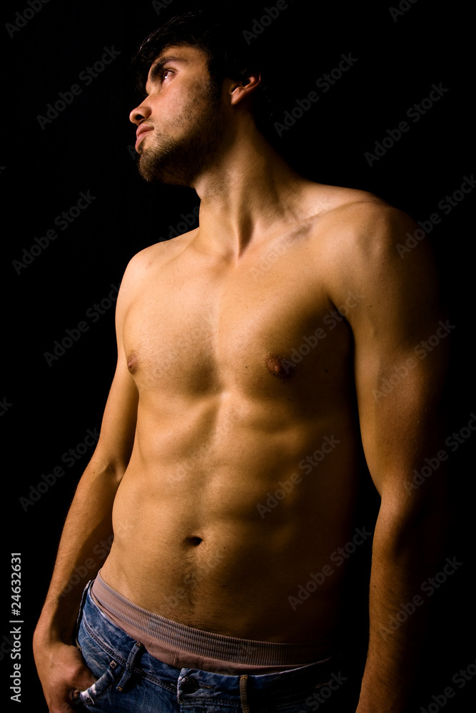 Fototapeta premium Young man with atletic body on black background