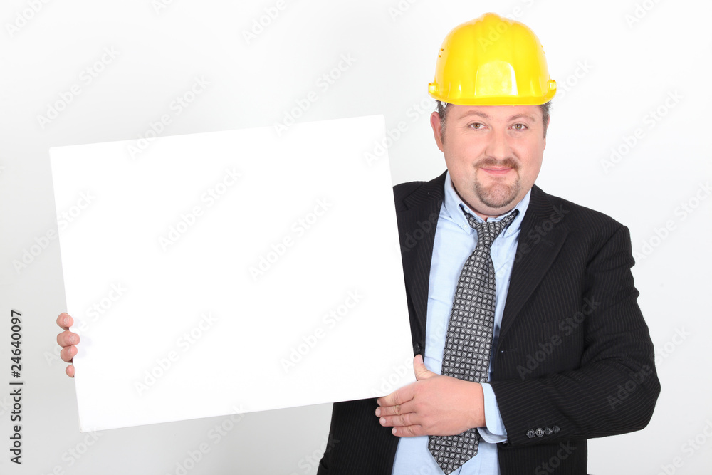 Homme en costume et casque de chantier avec un panneau blanc Homme en costume et casque de chantier avec un panneau blanc