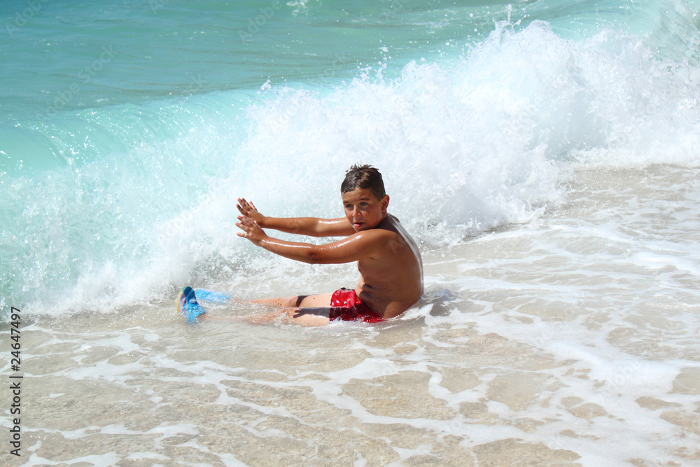 small boy sitting and stopping waves on sea