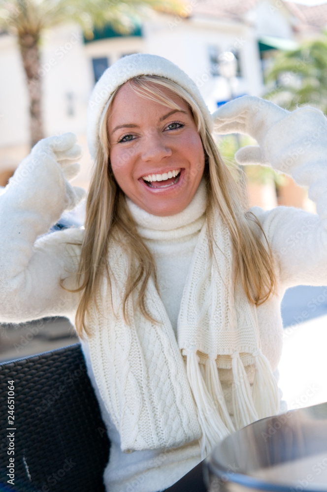 blonde woman smiling with white winter gloves and hat