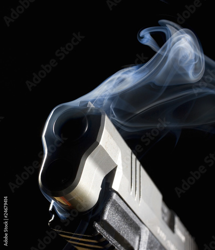 Mysterious pistol still belching smoke after being shot, with a black background behind