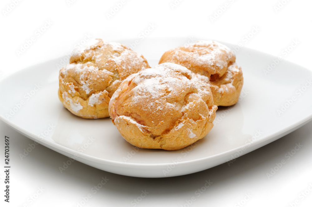 Three profiteroles on a plate, isolated, white background