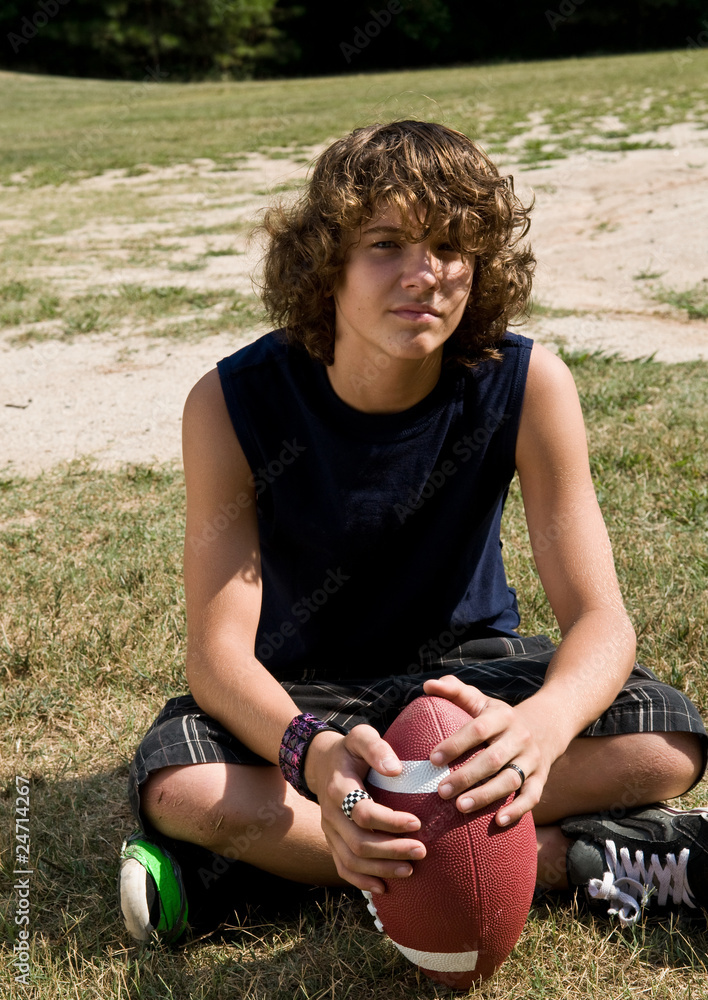 boy with long curly hair sitting, with football Stock Photo | Adobe Stock