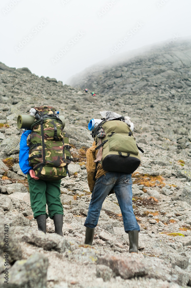 Two tired backpackers in mountains with knapsacks Two tired backpackers in mountains with knapsacks