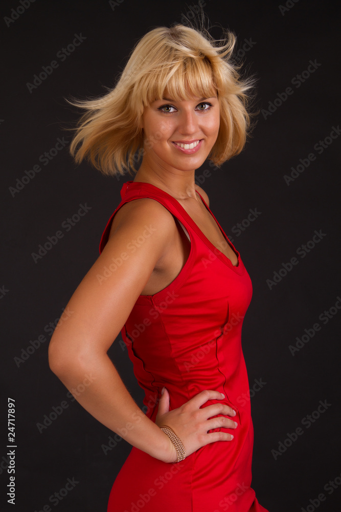 Charming lady in red evening dress, on black background.