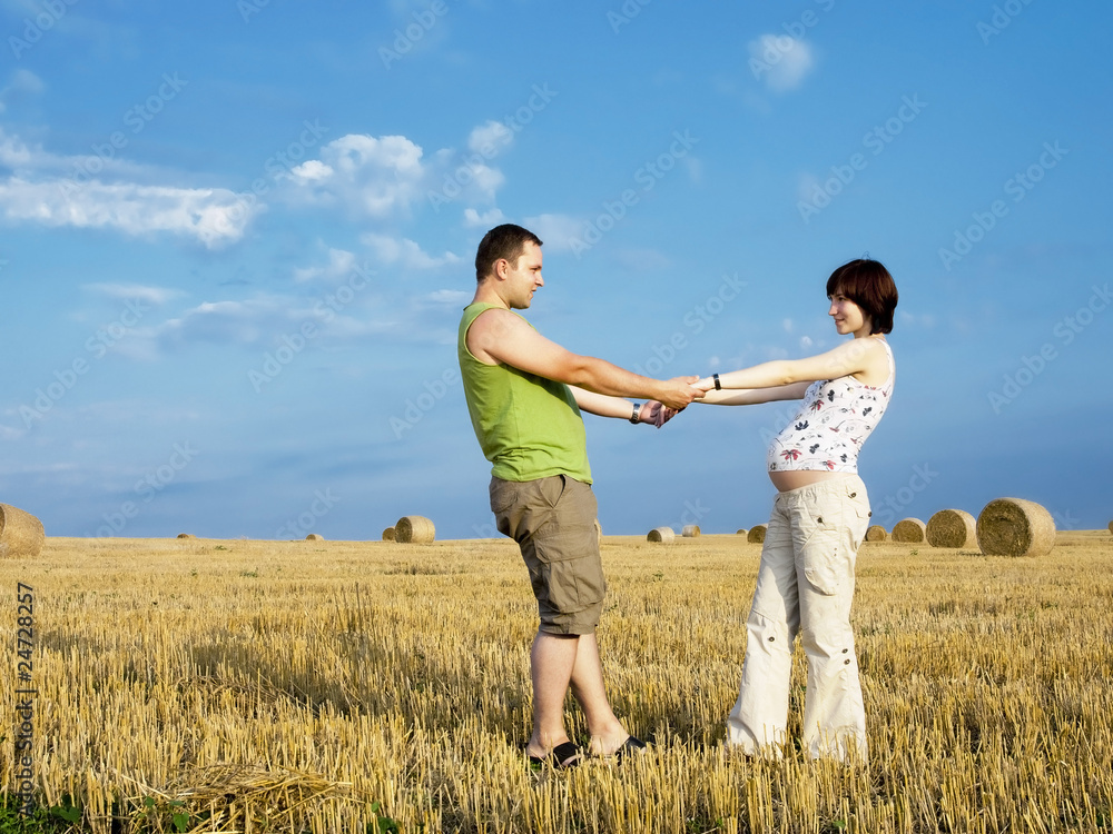 Young pregnant woman with husband in the meadow Young pregnant woman with husband in the meadow