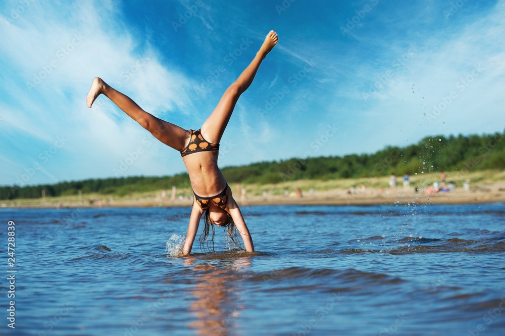 young girl making cartwheel in the water young girl making cartwheel in the water