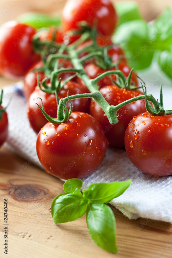 Fresh cherry tomatoes and basil on kitchen table Fresh cherry tomatoes and basil on kitchen table