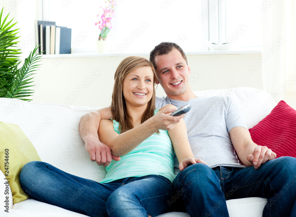 Charismatic man embracing his girlfriend while watching tv