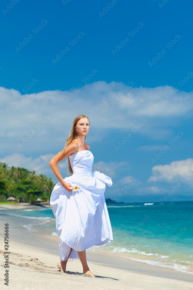 Bride walking along sea coast in the wedding dress