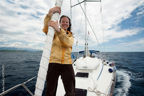 Young woman in yellow jacket having fun on the front of a yacht