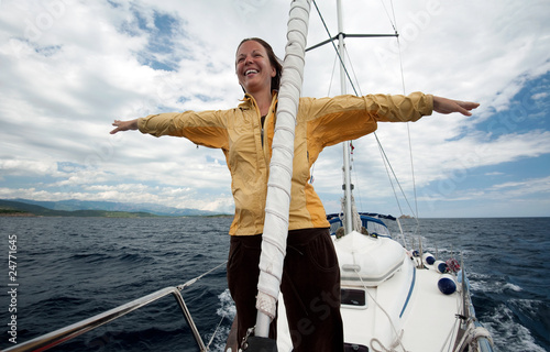Young woman in yellow jacket having fun on the front of a yacht