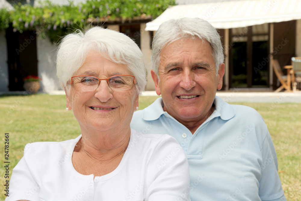 Senior couple sitting in front of a house Senior couple sitting in front of a house