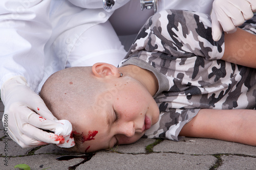 A lying boy in coma with injured head, doctor nearby