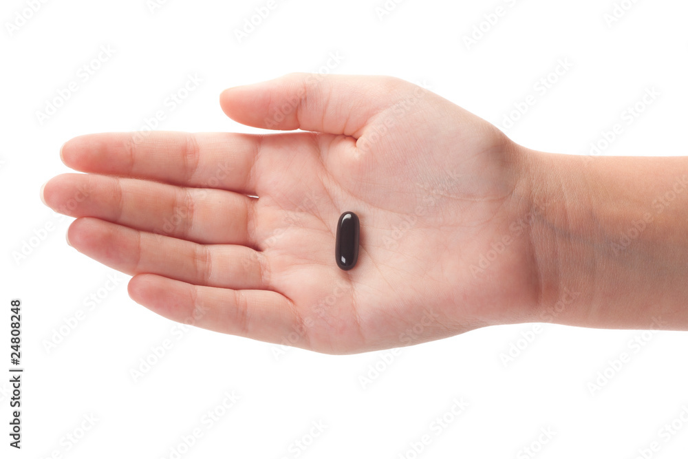 emale hand holding a black capsule, isolated emale hand holding a black capsule, isolated