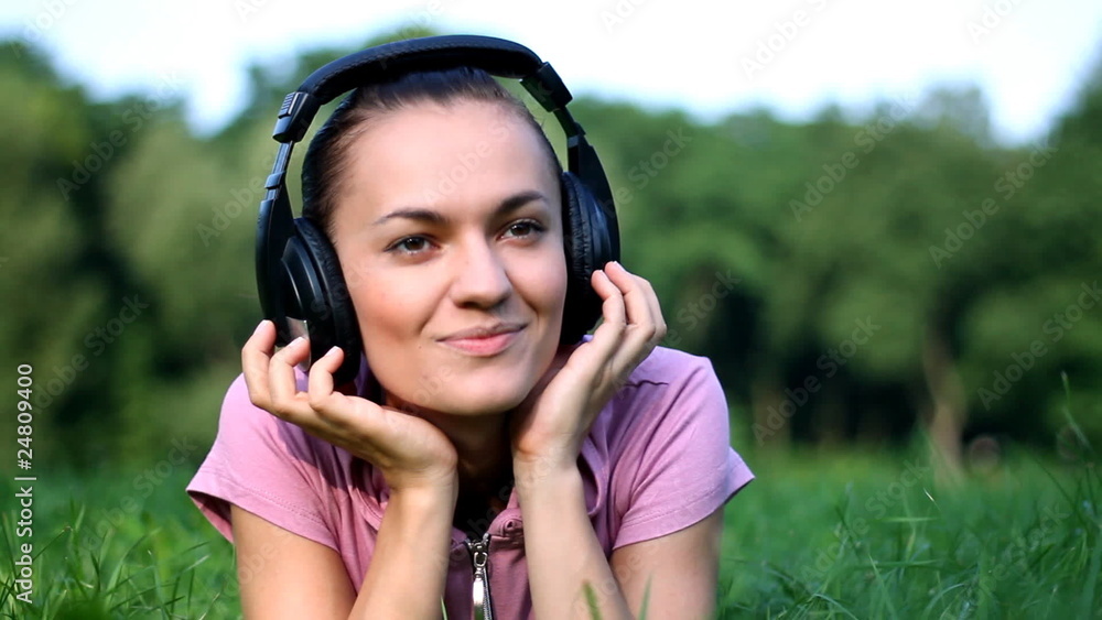 Attractive woman with headphones lying on the grass Attractive woman with headphones lying on the grass