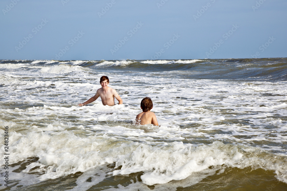 boys enjoying the waves in the wild ocean boys enjoying the waves in the wild ocean