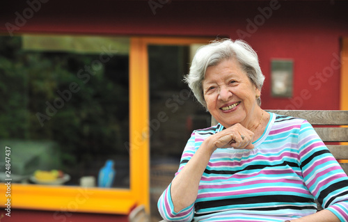 Senior Woman sitting in Front of Her House