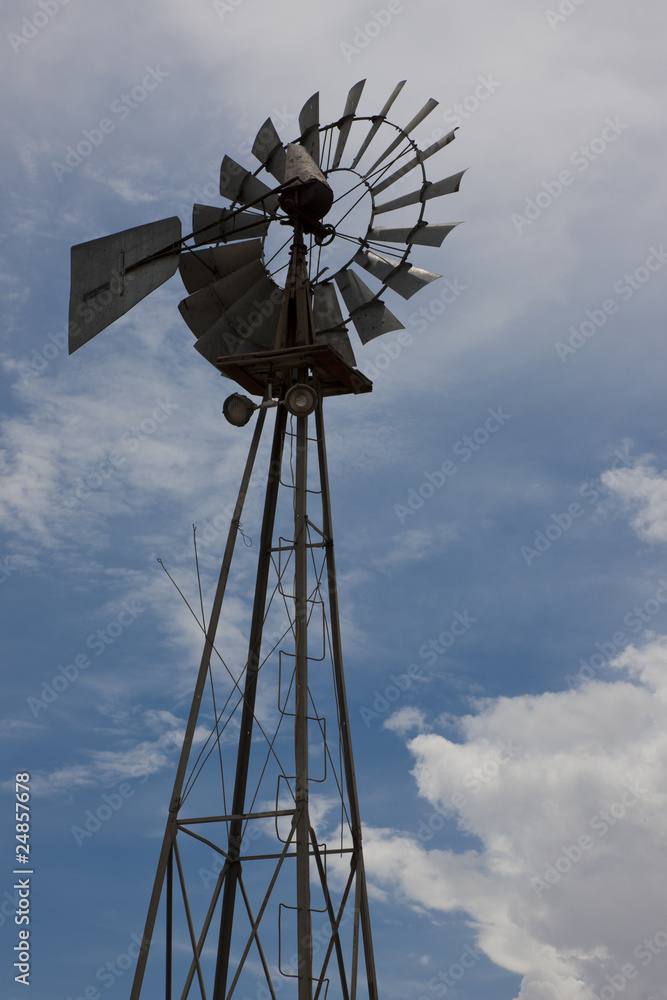 Rural Windmill Backlit Against Partly Cloudy Sky Rural Windmill Backlit Against Partly Cloudy Sky