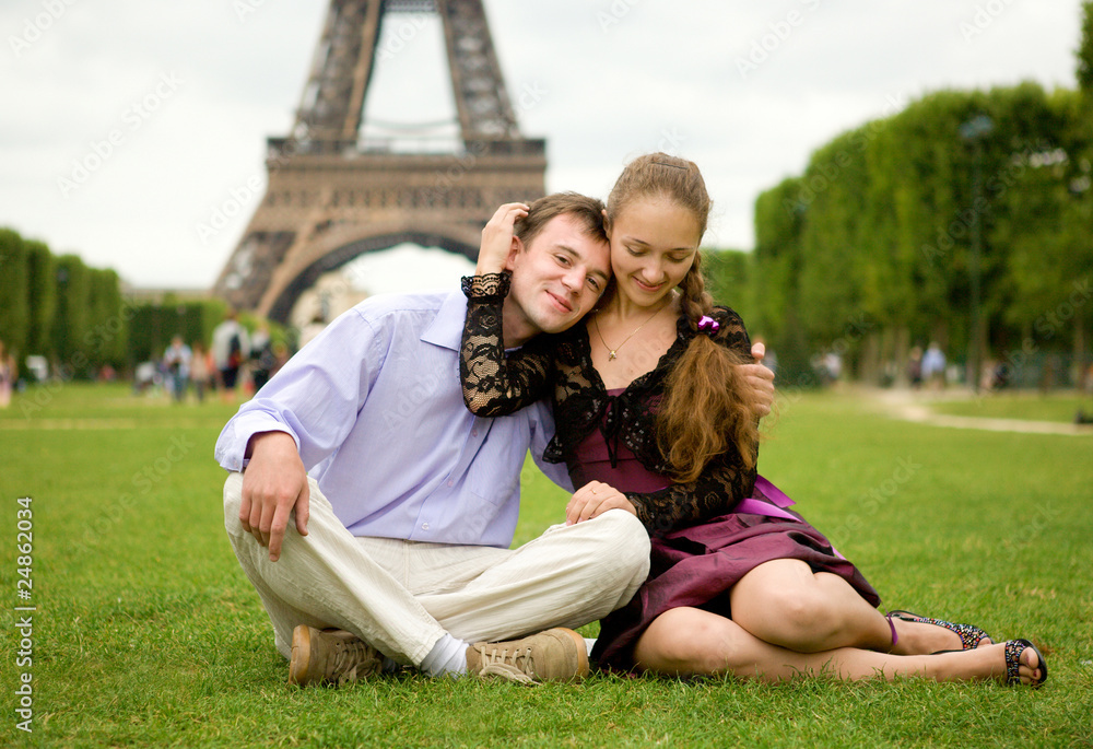 Happy romantic couple in Paris, sitting on grass by the Eiffel T Happy romantic couple in Paris, sitting on grass by the Eiffel T