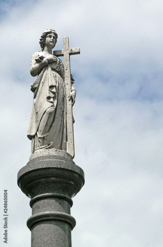 Female figure cemetary statue with cross atop pillar