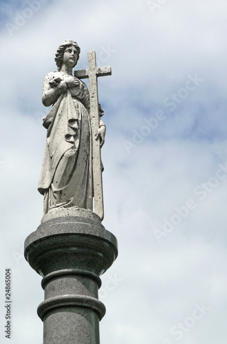 Female figure cemetary statue with cross atop pillar