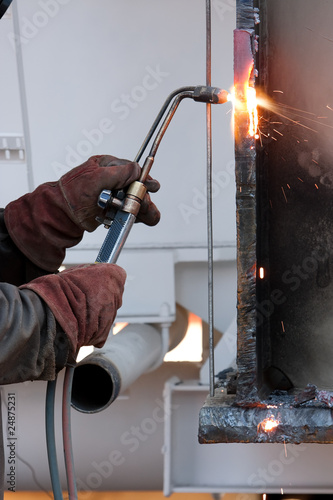 worker inside factory cut metal using blowtorch
