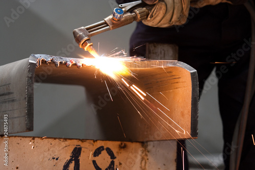 worker inside factory cut metal using blowtorch photo