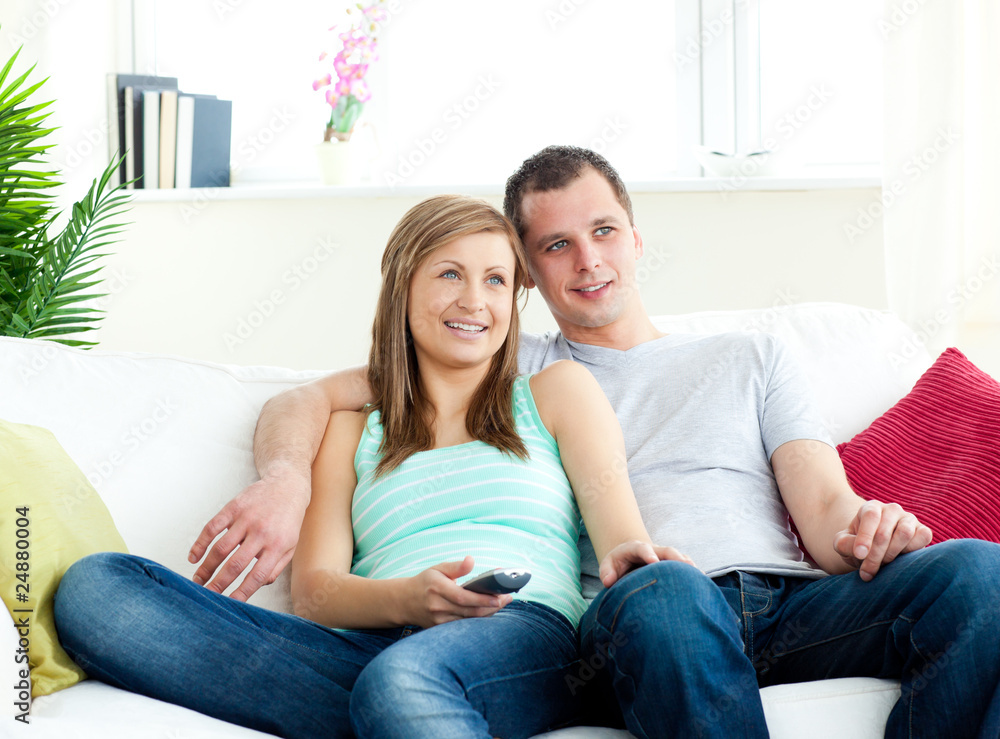 Attentive young couple sitting on the sofa watching tv Attentive young couple sitting on the sofa watching tv
