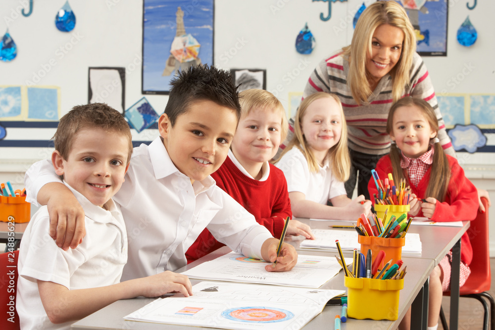 Group Of Primary Schoolchildren And Teacher Working At Desks In Group Of Primary Schoolchildren And Teacher Working At Desks In