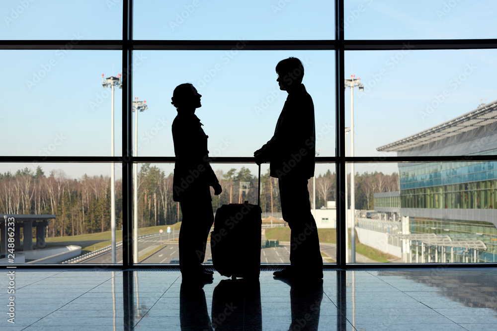 silhouette of man and girl with luggage standing near window