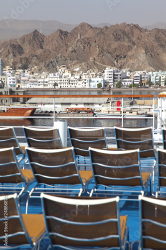 brown beach chairs on ship deck in port near mountains