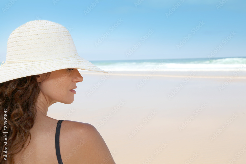Beautiful woman sitting on the beach with straw hat Beautiful woman sitting on the beach with straw hat
