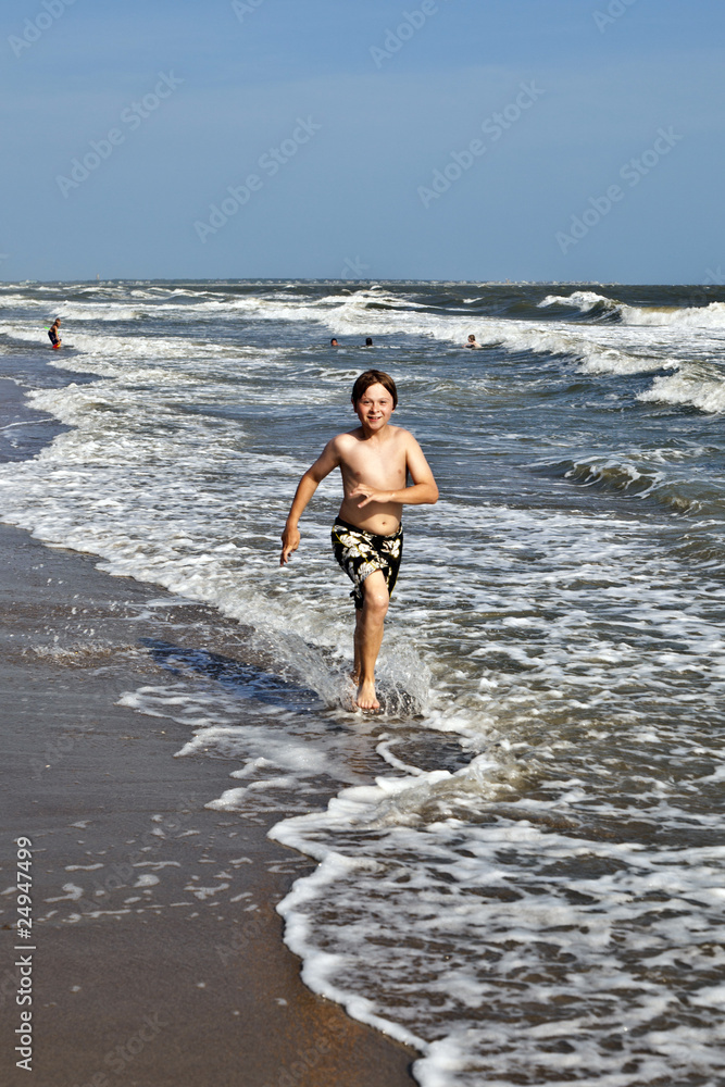 boy running along the beautiful beach in the waves