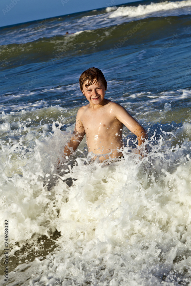 young boy enjoys the waves of the blue sea young boy enjoys the waves of the blue sea