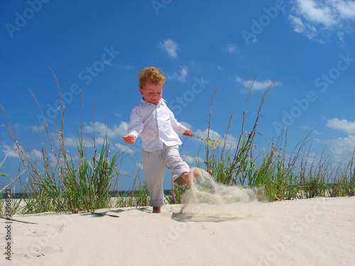 Boy kicking sand