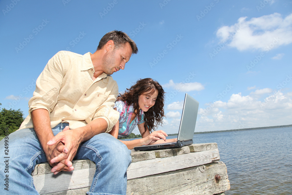 couple using laptop computer on a pontoon