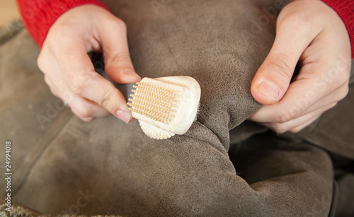 Woman cleaning a sheepskin with whisk broom photo