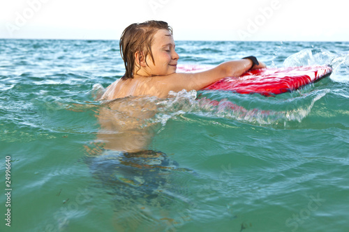 happy boy enjoys the crystal clear water with his surfboard