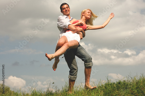 Happy young couple jumping in sky above a green meadow