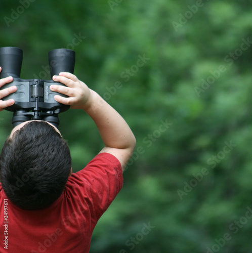 boy looking through binoculars in forest