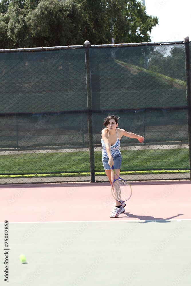 young hispanic teen girl swinging tennis racket